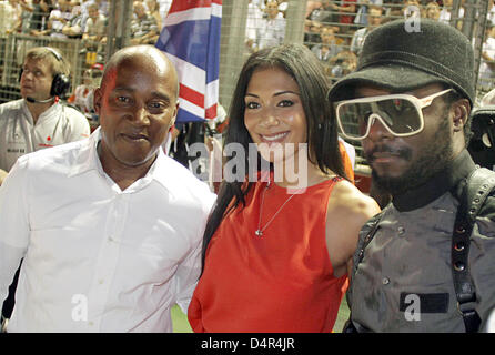 (L-R) Antony Hamilton, Vater des britischen Formel1-Fahrer Lewis Hamilton, Nicole Scherzinger, Freundin von Formel-1-Pilot Lewis Hamilton und Sänger der Band Pussycat Dolls und William James Adams aka Will.i.am von den Black Eyed Peas, posieren in das Gitter vor dem Formel 1 Singapur Grand Prix am Marina Bay Street Circuit in Singapur, Singapur, 27. September 2009. P Stockfoto