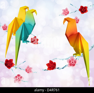 Origami-Papageien auf eine Äste von Bäumen mit Blumen auf rosa Hintergrund Stockfoto