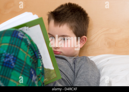 Bett Zeit Lesung im Schlafanzug; acht Jahre alten Kind Lektüre seines Buches vor Schlafenszeit. Stockfoto