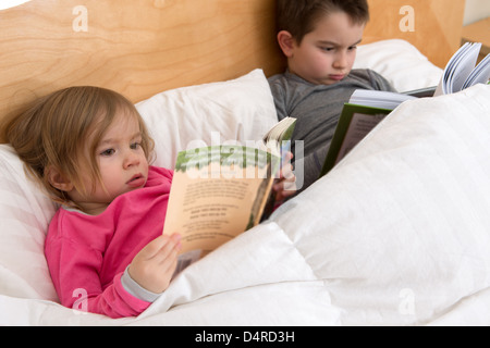 Lesegewohnheiten beginnt mit frühen Alter; Geschwister sind ihre Bücher vor dem Einschlafen lesen. Vielleicht gerade niedlich Kleinkind Stockfoto