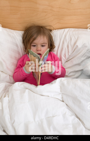 Lesegewohnheiten beginnt mit frühen Alter, niedlichen Kleinkind ist gerade die Seiten in ihrem rosa Schlafanzug bevor sie schlafen geht. Stockfoto