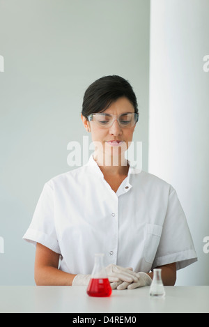Frau betrachten Labor Fläschchen mit Flüssigkeit gefüllt Stockfoto