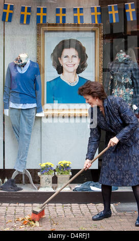 Eine Frau fegt die Promenade vor ein Mode-Boutique-Schaufenster zeigt ein Foto von Königin Silvia von Schweden in Bad Iburg, Deutschland, 16. Oktober 2009. Königin Silvia vergeben werden die? Mut-Preis? für die Gründung der? Die World Childhood Foundation? in Bad Iburg am 16. Oktober 2009. Der Preis ist mit 5.000 Euro dotiert. Foto: FRISO GENTSCH Stockfoto