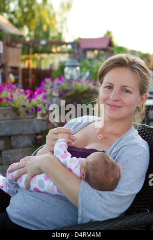 Blonde Mutter und neugeborene Tochter glücklich hand zu hand mit der auf der Terrasse in der Nachbarschaft, sie ist 7 Tage alt. Stockfoto