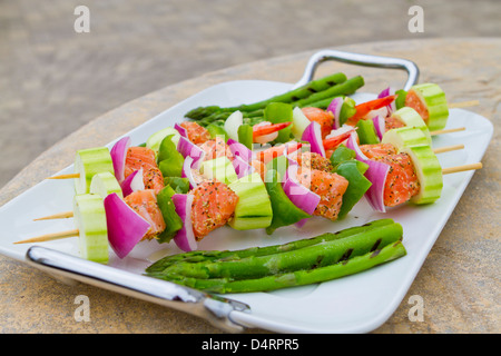 Lachs Würfel und Garnelen mit Gemüse am Spieß ergänzt. Rote Zwiebeln, Zucchini, Paprika und Spargel. Stockfoto