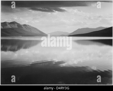 Ansel Adams hielt die ruhige Schönheit des McDonald Lake im Glacier National Park während einer Abendszene fest. Das Schwarzweiß-Bild zeigt die majestätische Landschaft und die natürliche Gelassenheit des Parks in Montana. Stockfoto