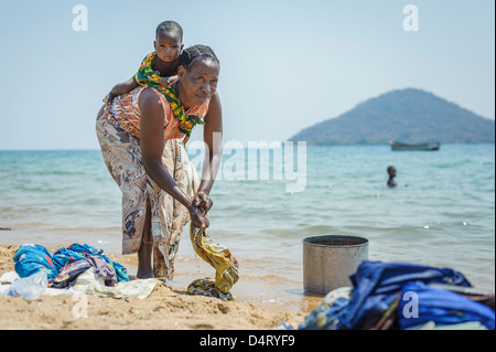 Frau mit Kind, die Wäsche am Ufer des Lake Malawi, Malawi, Afrika Stockfoto
