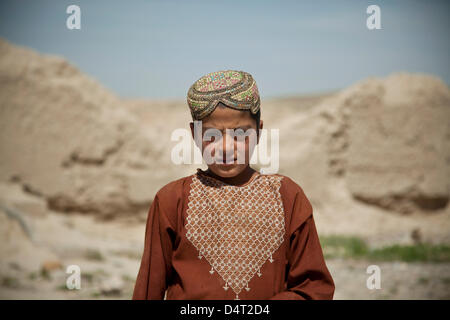 Ein afghanischer Junge in traditioneller Kleidung Watch US Special Forces und Afghan National Army Special Forces Begleitung einen Distrikt-Governor 17. März 2013 in der Provinz Helmand, Afghanistan. Stockfoto