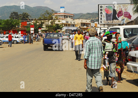 Bujumbura, Burundi-Fahrzeuge mit Menschen auf der Straße mit Häusern im Hintergrund in der Stadt. (MR) Stockfoto