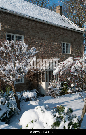 Winterszenen rund um Doncaster mit einem schneebedeckten Steinhaus, einer Person, die durch einen frostigen Waldweg geht, und Fußspuren über verschneite Fälle Stockfoto