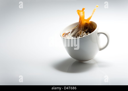 Fallenden Tasse Kaffee vor einem weißen Hintergrund Stockfoto