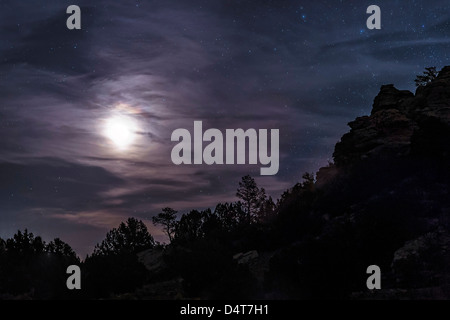 Ein heller Mond steigt durch Wolken über einen Hügel in Oklahoma, USA. Stockfoto