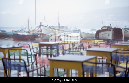 Mykonos Waterfront Café mit Fischen Boates verankert im Hafen an regnerischen Tag Stockfoto