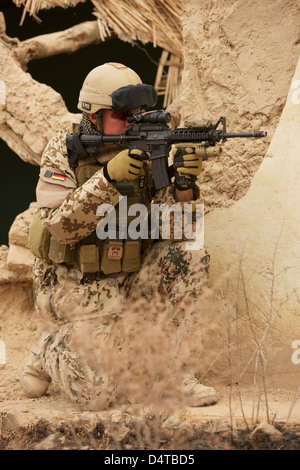 Ein Soldat der deutschen Armee bewaffnet mit einer M4 Karabiner Sturmgewehr in den Ruinen von einem afghanischen Gebäude. Stockfoto