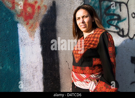 Eine stolze palästinensische Frau stehend durch die Barriere, die von der israelischen Regierung gebaut. Art und Graffiti schmücken diese Betonwand. Stockfoto