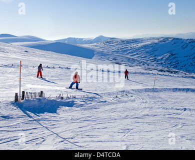 2 Snowboarder und Skifahrer auf der Piste, Cairngorm Mountain Ski Centre in der Nähe von Aviemore, schöner sonniger Tag, Cairngorms, Schottland, Vereinigtes Königreich Stockfoto