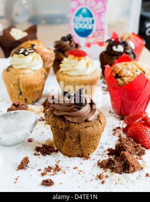 Ein Schokoladen-Kaffee-Muffin, umgeben von Krümel mit anderen Muffins im Hintergrund Stockfoto