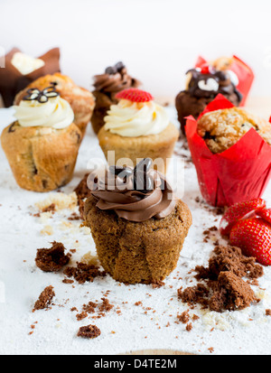 Ein Schokoladen-Kaffee-Muffin, umgeben von Krümel mit anderen Muffins im Hintergrund Stockfoto