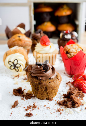 Ein Schokoladen-Kaffee-Muffin, umgeben von Krümel mit anderen Muffins im Hintergrund Stockfoto