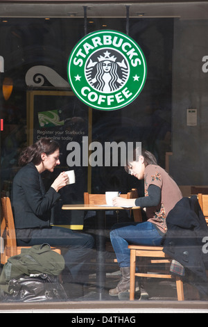Zwei Frau saß am Fenster in eine Filiale von Starbucks Coffee, am Strand, zentrales London, England, UK Stockfoto