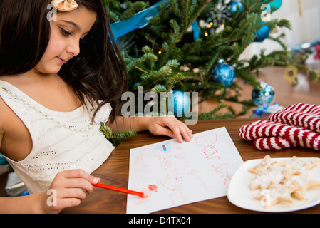 Mädchen am Tisch Brief an den Weihnachtsmann schreiben Stockfoto