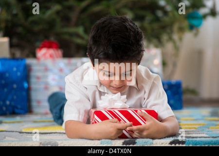 Junge hält Weihnachtsgeschenk Erdgeschoss Stockfoto