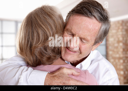 Älteres Ehepaar im Wohnzimmer umarmt Stockfoto