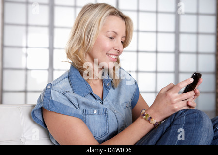 Frau mit Handy auf sofa Stockfoto