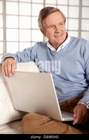 Älterer Mann mit Laptop auf sofa Stockfoto