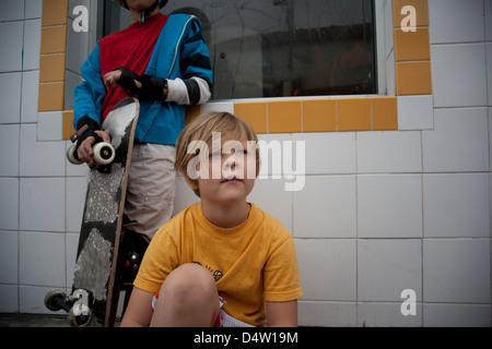 Jungen mit Skateboard sitzen im freien Stockfoto