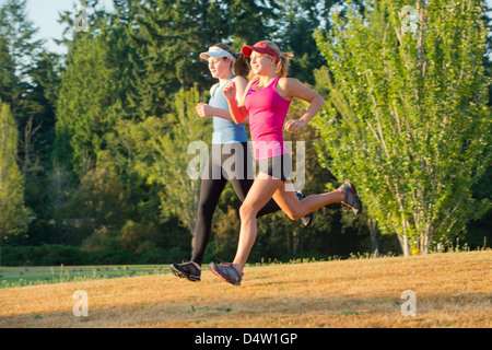 Mädchen im Teenageralter zusammen laufen im Feld Stockfoto