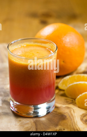 Ein Glas frisch gepresster Blutorangensaft mit ganzen Früchten und Segmenten. Stockfoto