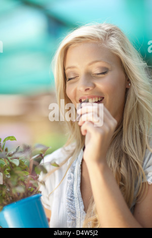 Frau riechende Pflanze im Kindergarten Stockfoto