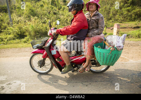 12. März 2013 - Luang Prabang, Luang Prabang, Laos - leitet ein paar auf einem Motorrad Nord auf der Autobahn 13. Die Pflasterung der Autobahn 13 von Vientiane bis nahe der chinesischen Grenze hat den Weg des Lebens im ländlichen Laos verändert. Dorfbewohner in der Nähe von Luang Prabang verwendet zu haben, um unzuverlässige Boote nehmen, die drei Stunden hin-und Rückfahrt dauerte, bis aus den Häusern zum touristischen Zentrum von Luang Prabang, jetzt sie eine 40-minütige Rundfahrt nehmen Busfahrt. Nördlich von Luang Prabang wurde die Pflasterung der Autobahnanschluss eine Chance für China, Laos als eine Umladung Punkt zu verwenden. Chinesische Ware geht jetzt durch Laos nach Thailand wo Stockfoto