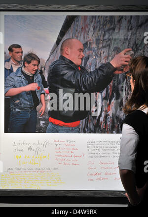 Eine Frau schaut ein Foto aus der Serie "The Fall" auf der Messe "und dann die Wand war verschwunden. Fotografien von Gilles Peress auf dem modernen historischen Forum in Leipzig, Deutschland, 21. September 2010. Die Ausstellung findet statt um die 20. fast der deutschen Wiedervereinigung zu feiern. Vom 22. September bis 14 November können die Bilder an drei Orten gesehen werden, die con Stockfoto