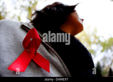 (Datei) - ein Dpa-Datei Bild datiert 6. November 2009 zeigt eine Frau trägt ein rotes Band zu sensibilisieren und die Solidarität der Menschen mit HIV/AIDS in Köln. Nach Brandenburgs Gesundheitsministerin Anita Tack unterschätzen Menschen die Gefahr von HIV-Infektionen. Foto: Oliver Berg Stockfoto