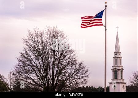 Werte der Gemeinschaft des Glaubens und der Patriotismus sind in den Symbolen der eine wehende Fahne und Kreuz-Spitze Kirchturm gesehen. Stockfoto