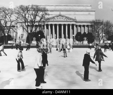 Dieses Foto zeigt die Seite der Constitution Avenue des National Archives mit einer Eislaufbahn davor. Es erfasst sowohl die architektonische Struktur als auch die öffentlichen Freizeitaktivitäten in Washington, D.C. Stockfoto