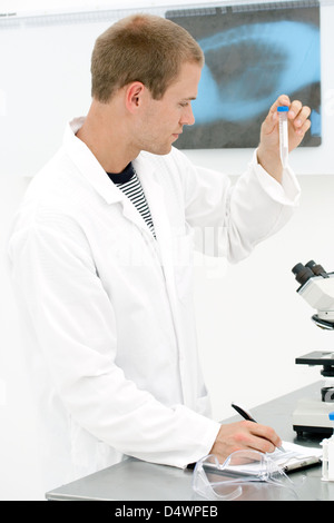 Eine junge männliche Lab Tech Blick auf Testproben im Labor Stockfoto