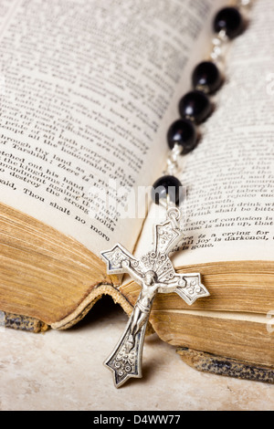 Rosenkranz und Kreuz liegend auf einer geöffneten Seite der Bibel. Stockfoto
