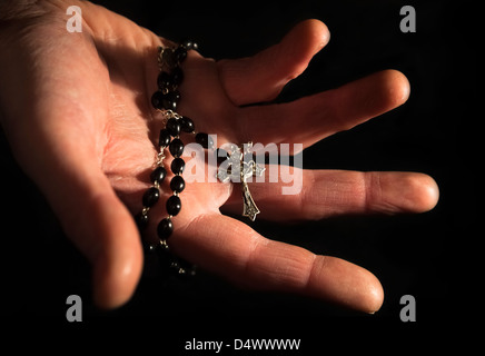 Helfende Hand festhalten Rosenkranz und Kreuz. Stockfoto