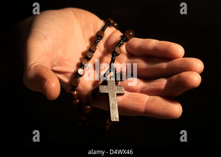 Helfende Hand festhalten Rosenkranz und Kreuz. Stockfoto