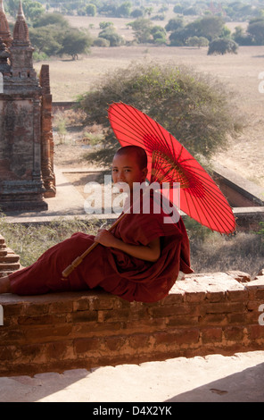 Junge Novize und Sonnenschirm, gerahmt in einem Torbogen Bagan-Tempel. Stockfoto