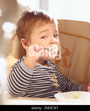 Zwei Jahre alter Junge isst Brei am Morgen. Stockfoto