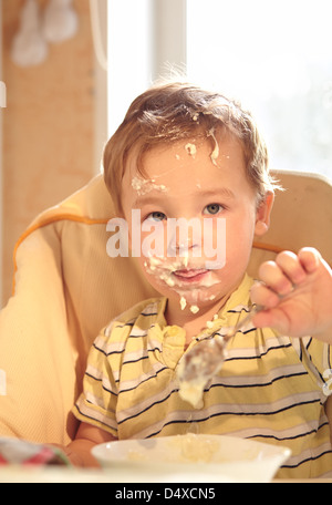 Zwei Jahre alter Junge isst Brei am Morgen. Stockfoto