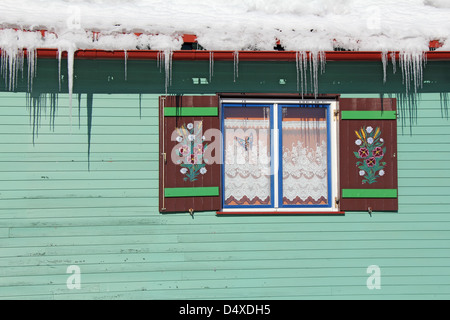 Holzfenster Bauernhaus handbemalt unter das Dach voller Schnee Stockfoto