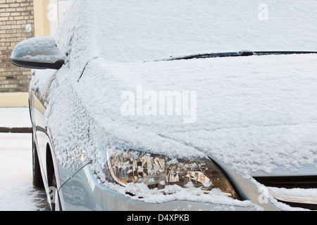 Fronthaube und Lichter der Europäischen Auto bedeckt mit einer Schicht Neuschnee während einer harten Winter-Saison Stockfoto