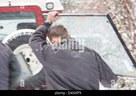 Glaser, die Durchführung einer Fensterscheibe im Schnee nach ihren Wagen auf einem steilen Hügel, Ambleside, Lake District, UK geklebt wurde. Stockfoto