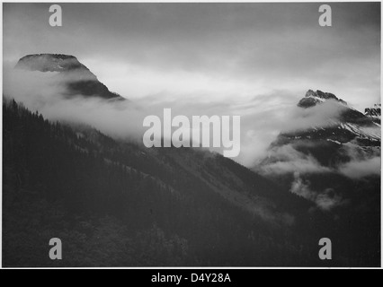 Ansel Adams hat dieses Schwarzweiß-Foto eines teilweise in Wolken gehüllten Berges im Glacier National Park in Montana aufgenommen. Das Bild spiegelt die majestätische Landschaft des Parks und seine natürliche Schönheit wider. Stockfoto