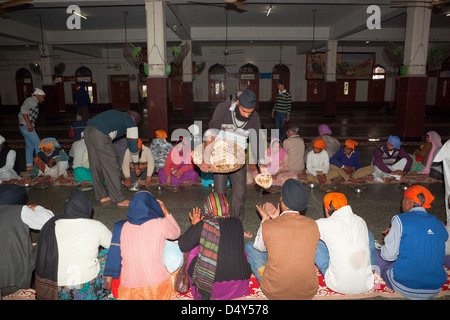 Pilger, die versorgenden Chapattis mit einer Mahlzeit im freien Küche im Inneren des goldenen Tempels Komplex in Amritsar Punjab, Indien Stockfoto